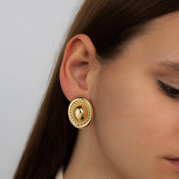 Golden-colored earrings in the shape of cufflinks