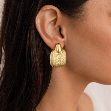 Golden, quadrilateral earrings with a pattern resembling the texture of a sweater