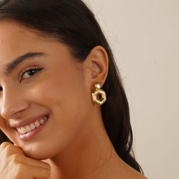 Golden, hammered hexagonal hoop earrings with concave and convex stripes