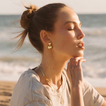 Golden-colored earrings with two interconnected spheres