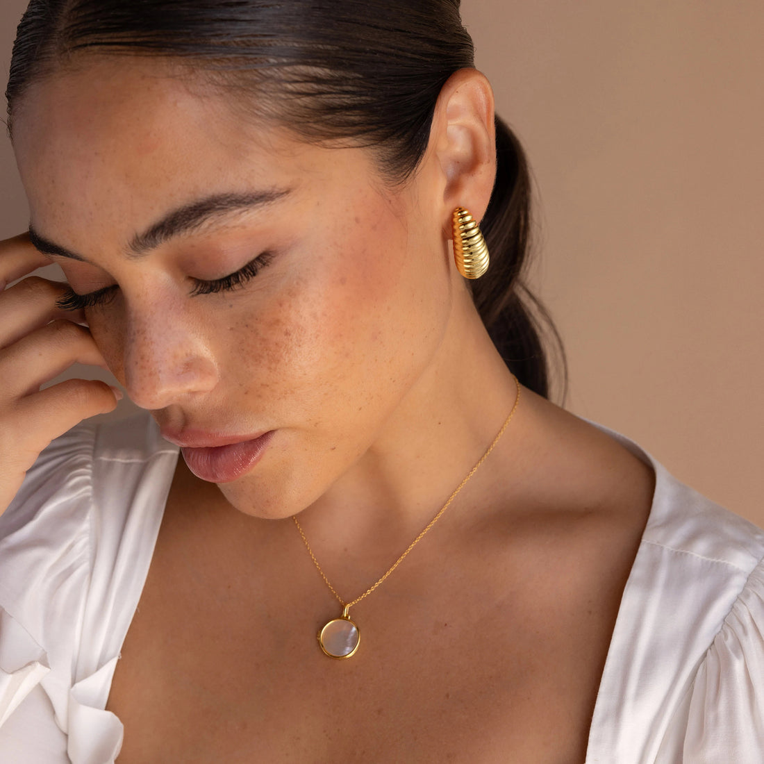 Golden-colored earrings in the shape of a small silkworm pupa