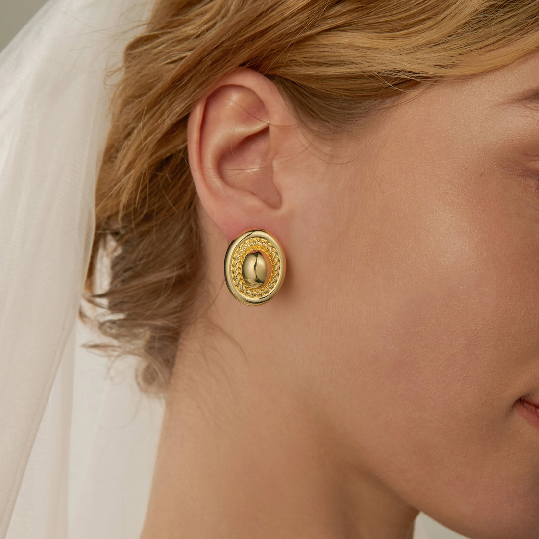 Golden-colored earrings in the shape of cufflinks