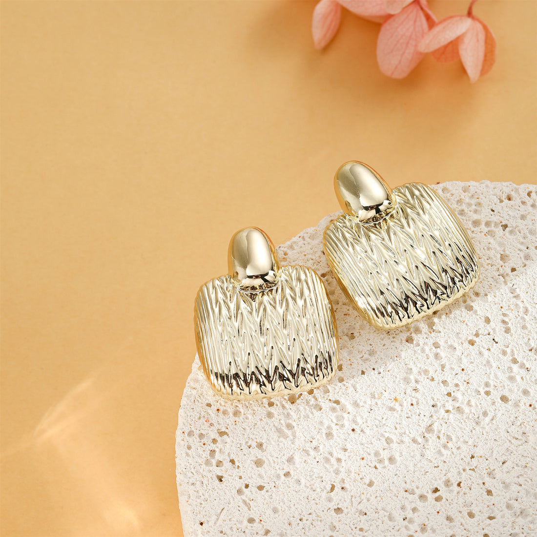 Golden, quadrilateral earrings with a pattern resembling the texture of a sweater