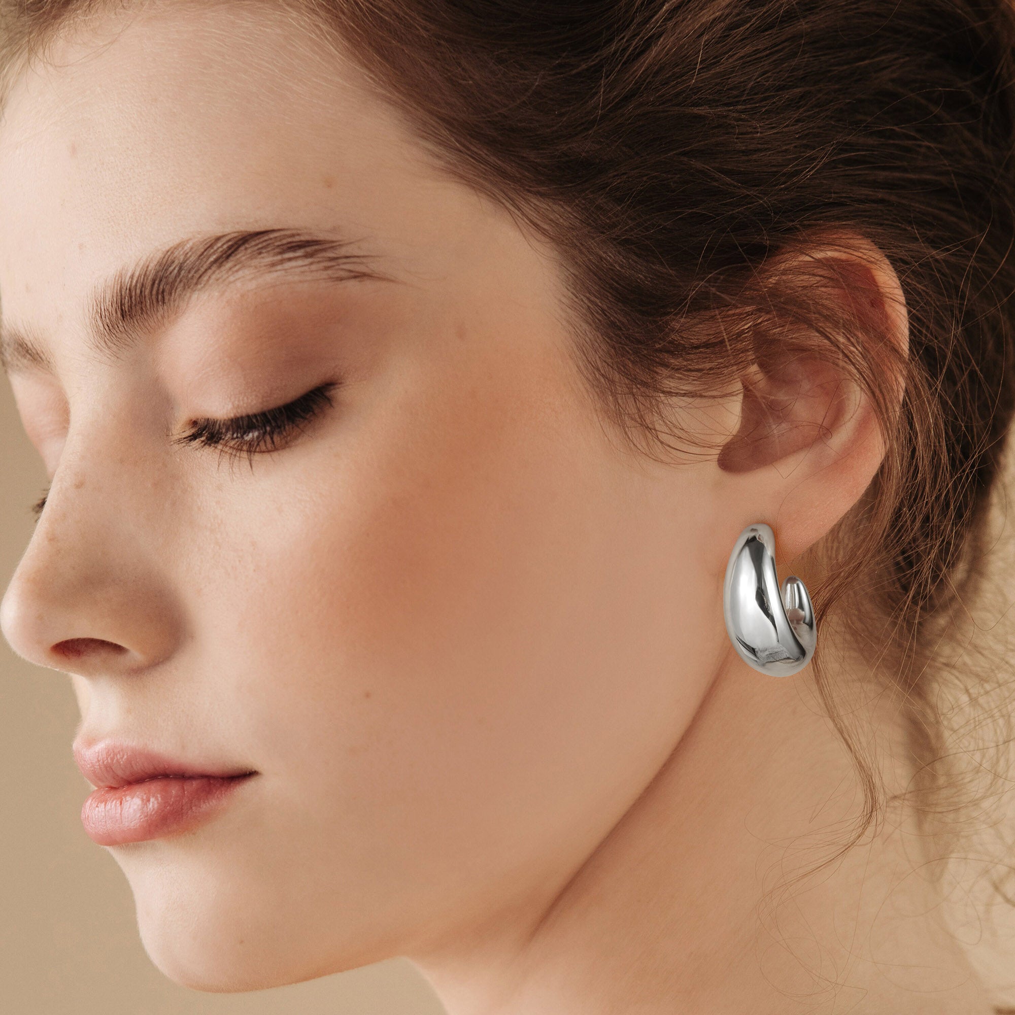 Golden/Silvery-colored, C-shaped earrings with two pointed tips and a wide middle