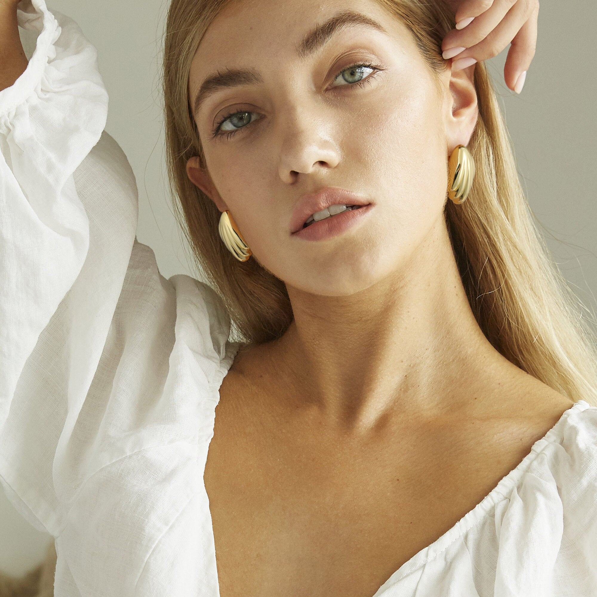 Golden-colored earrings shaped like a bird's tail