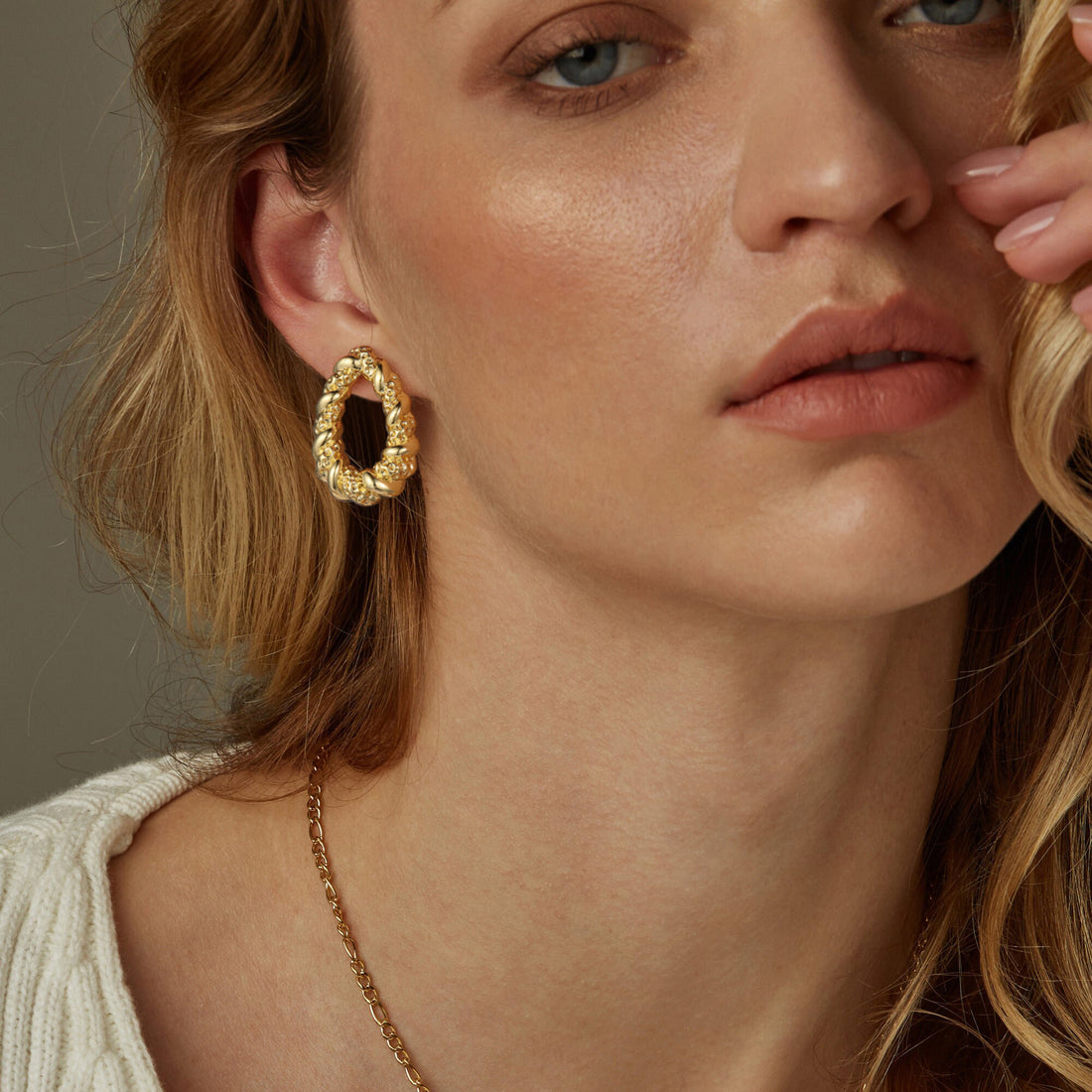 Golden O-shaped hoop earrings with a pattern of two intersecting strands