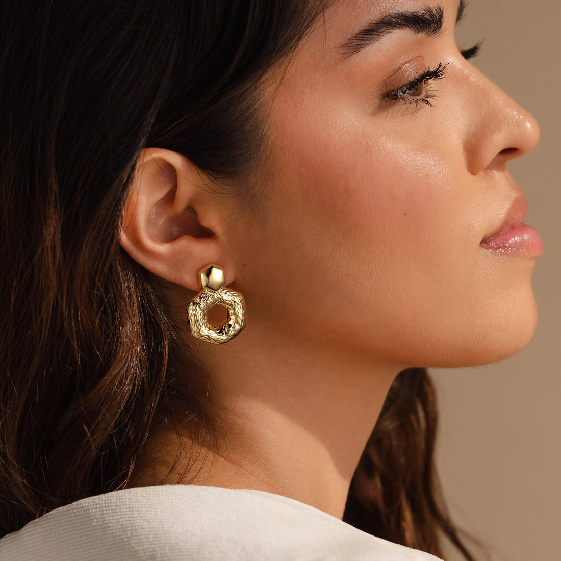 Golden, hammered hexagonal hoop earrings with concave and convex stripes
