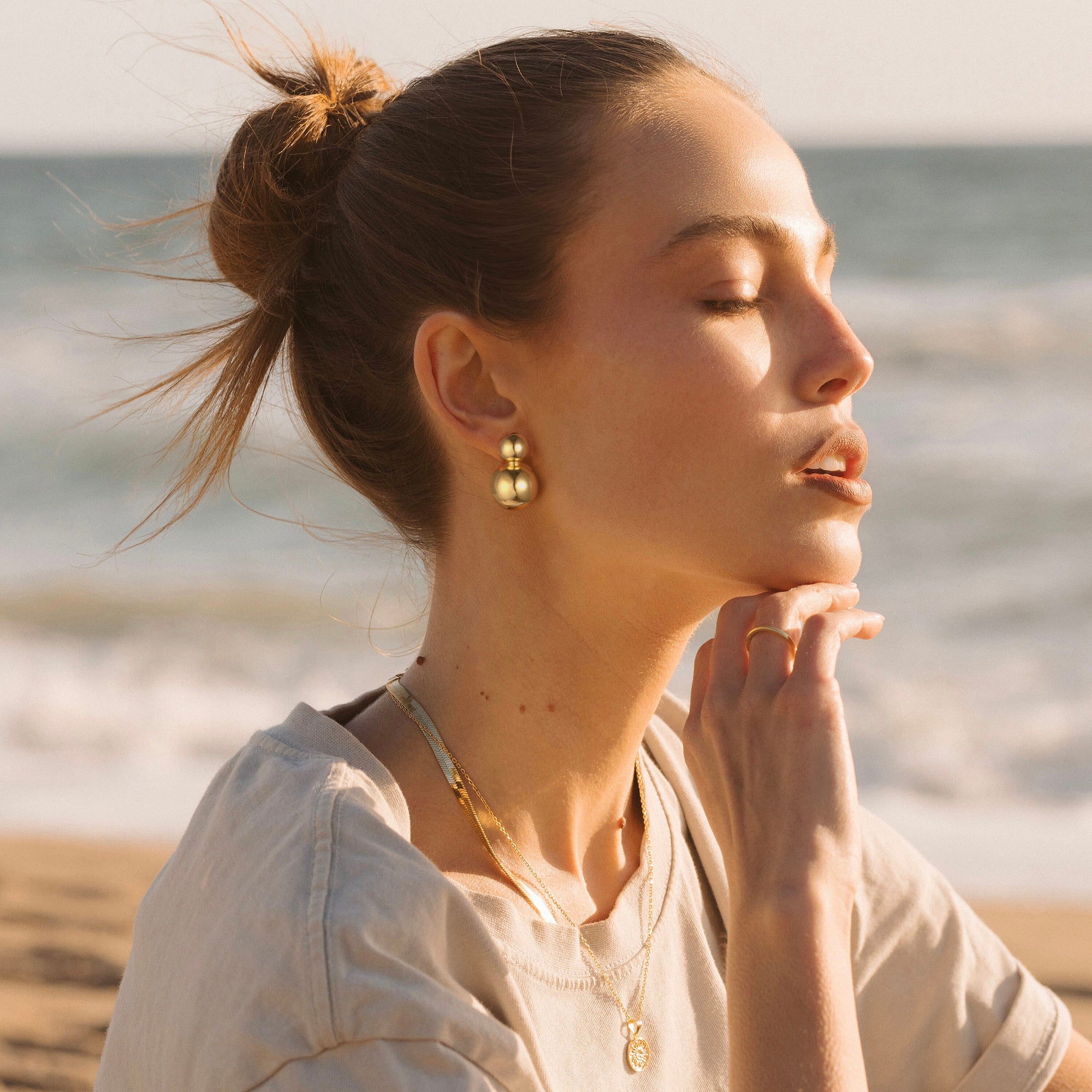 Golden-colored earrings with two interconnected spheres