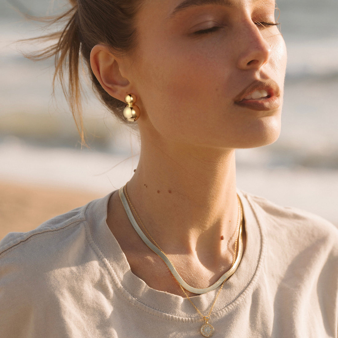 Golden-colored earrings with two interconnected spheres